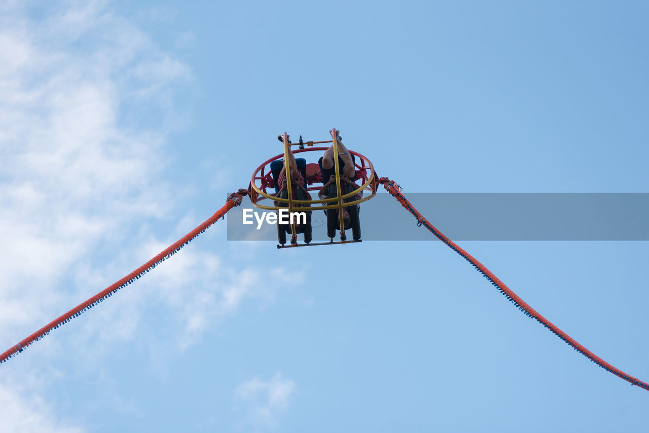 LOW ANGLE VIEW OF WORKING AGAINST SKY