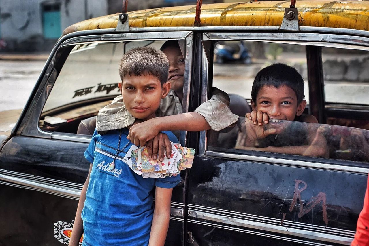 PORTRAIT OF TWO MEN ON CAR