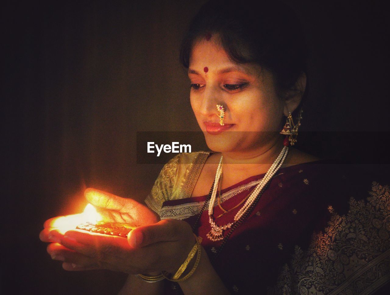 Close-up of woman holding diya in dark