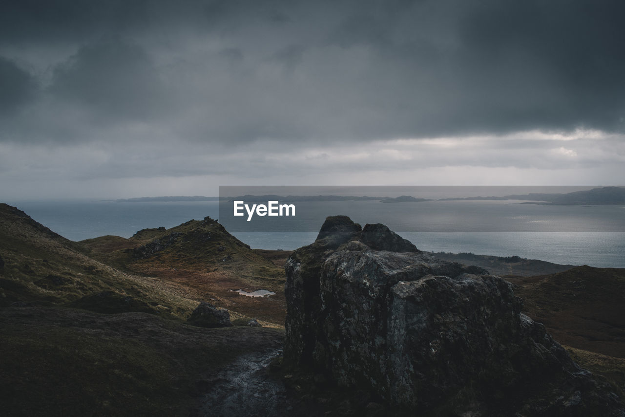 Scenic view of rocky mountains by sea against sky