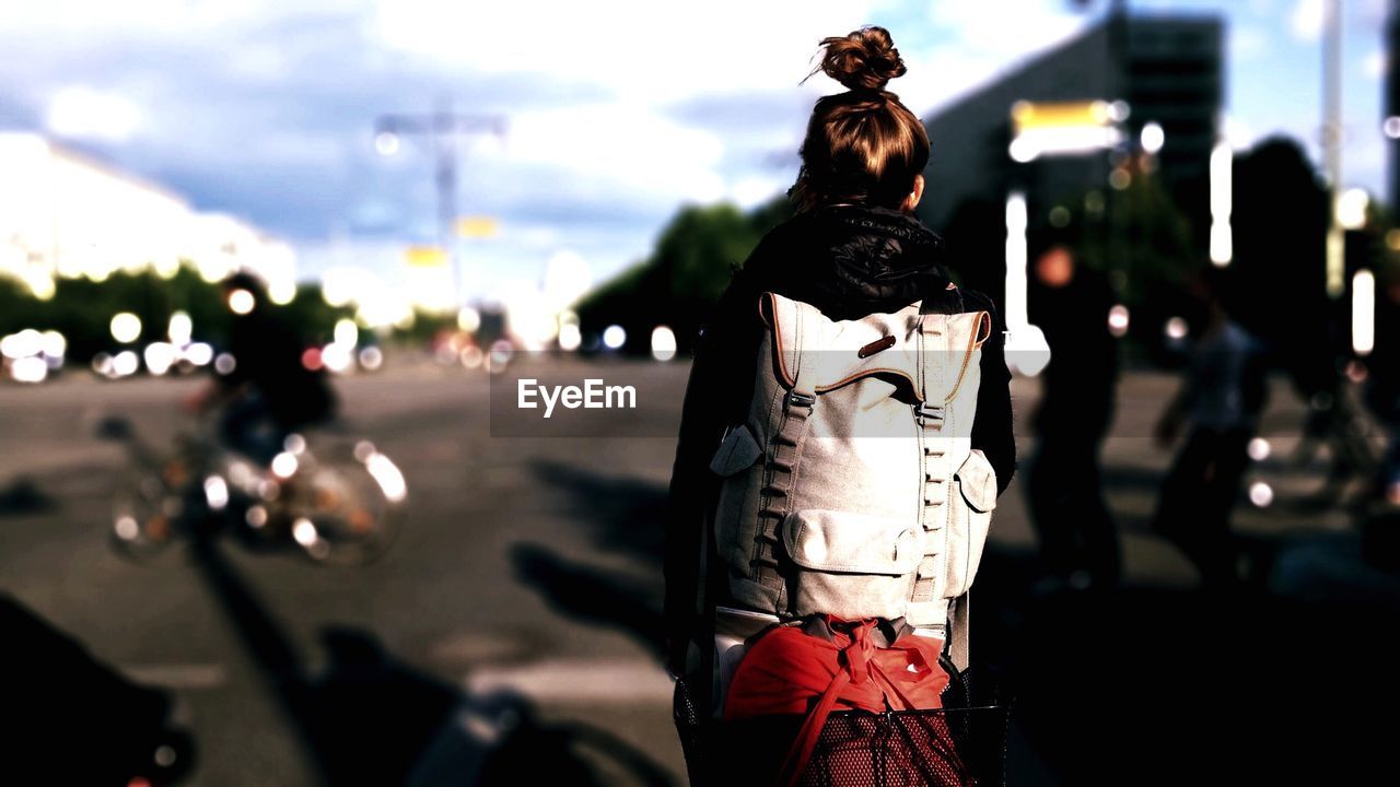Rear view of woman with backpack standing on street