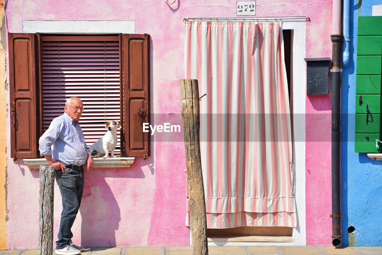 FULL LENGTH OF MAN STANDING ON BUILDING WINDOW