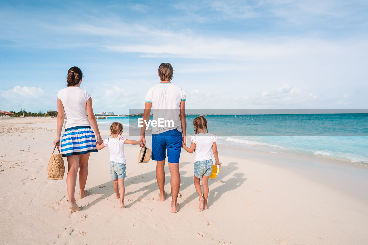 REAR VIEW OF PEOPLE ENJOYING ON BEACH