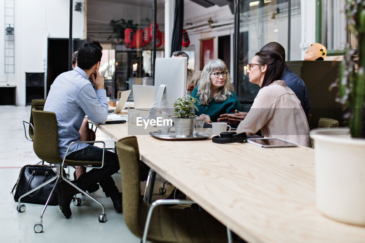 Male and female coworkers discussing at table in business meeting