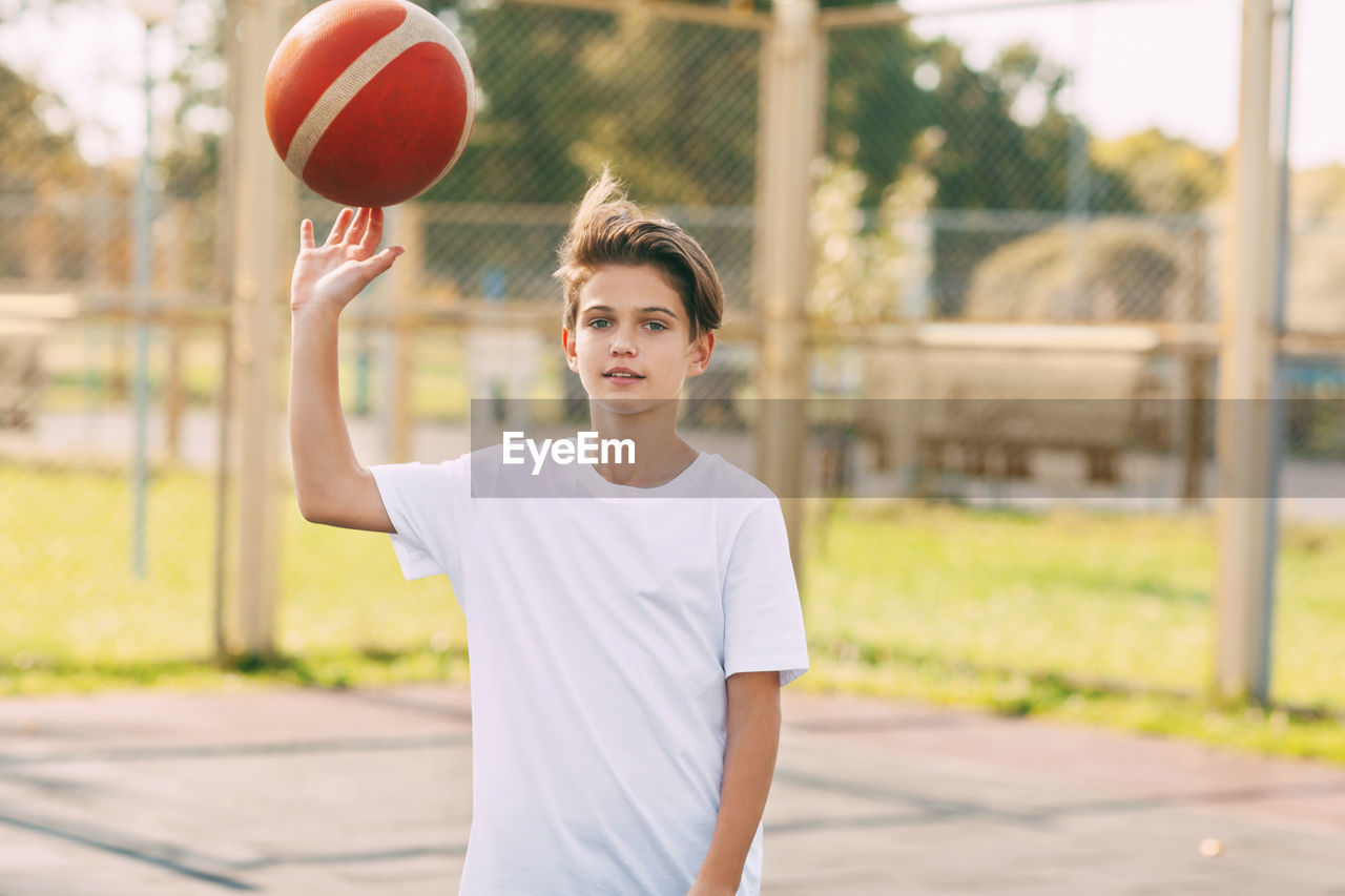 Portrait of boy playing with basketball at court