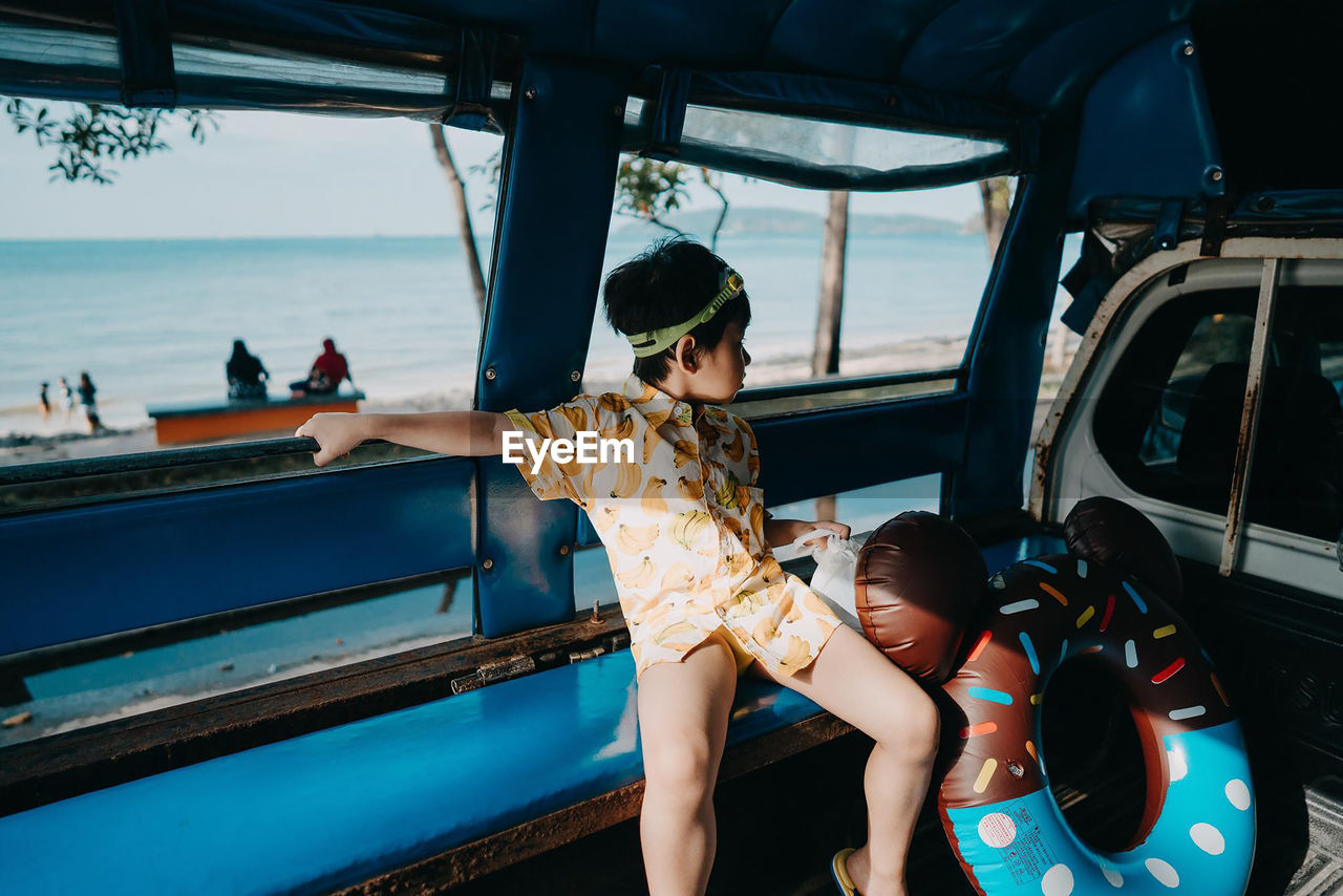 Boy sitting in vehicle at beach