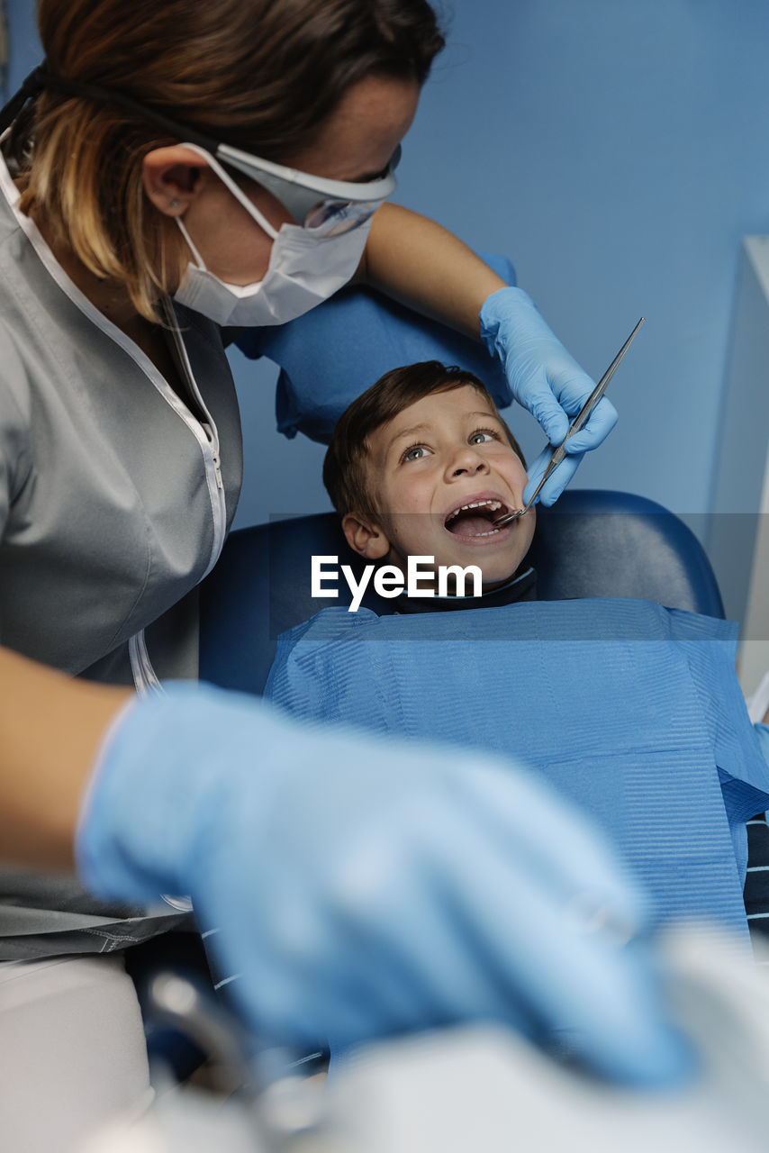 Dentist operating boy in medical clinic