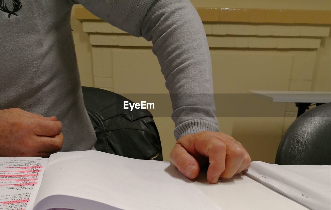 MIDSECTION OF MAN WORKING WITH TATTOO ON TABLE