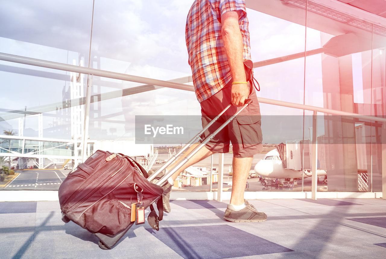 Low section of man walking at airport against sky