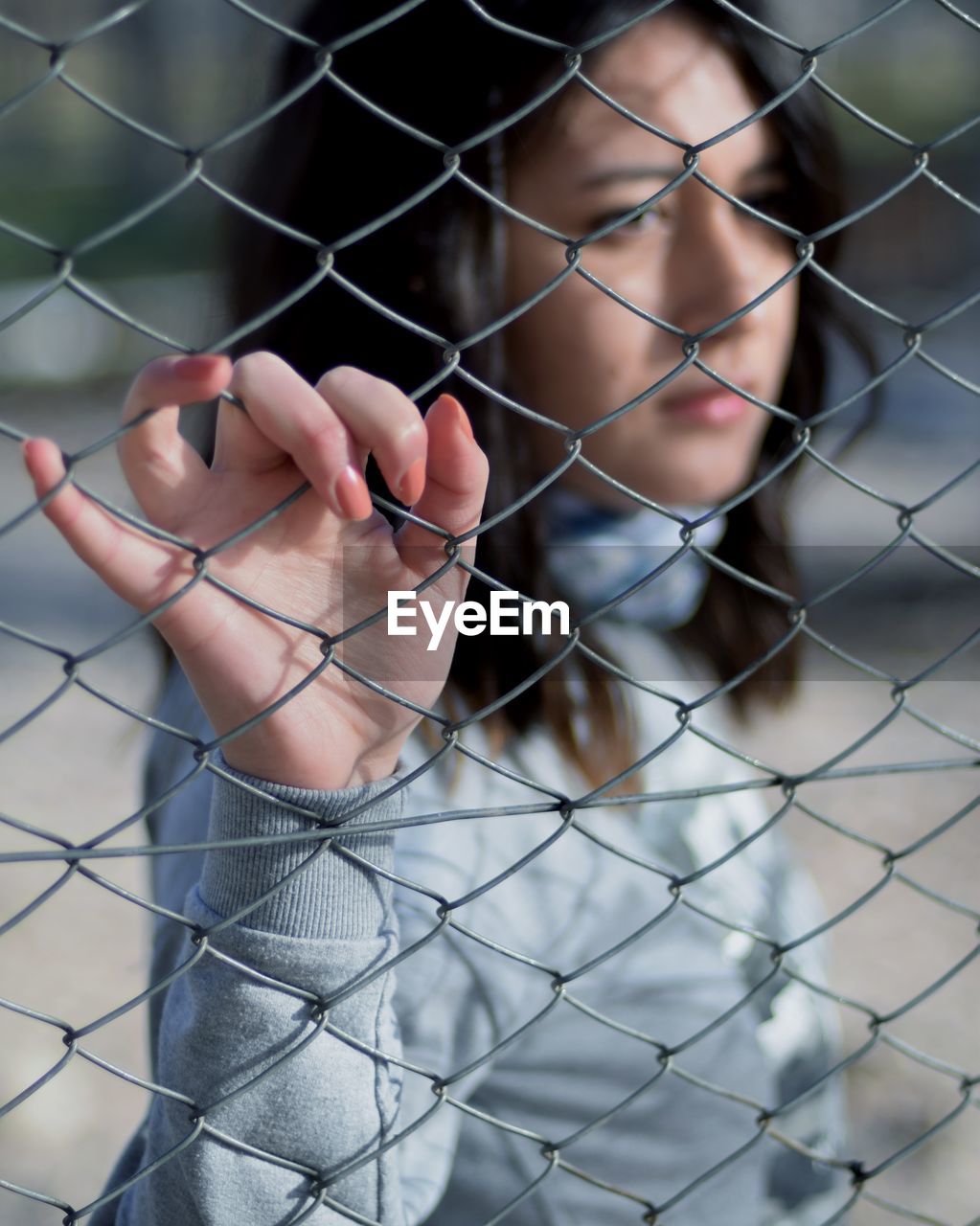 Close-up of hand holding chainlink fence