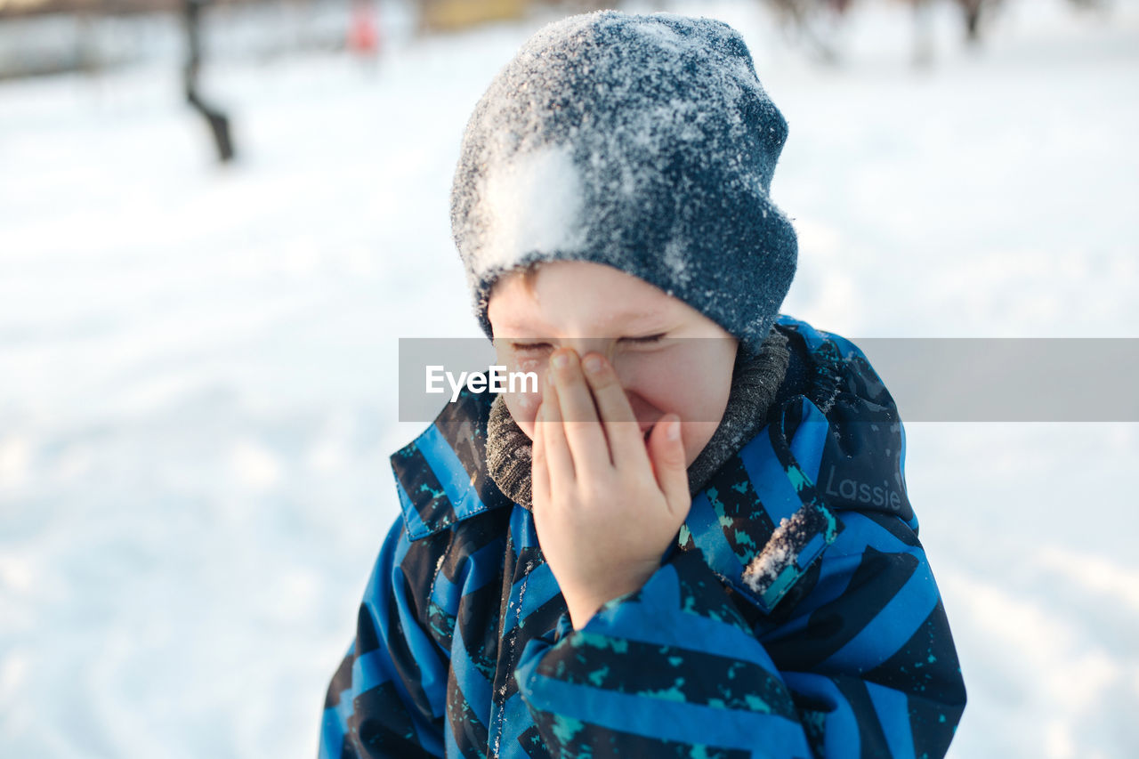 Close-up of smiling boy in snow outdoors