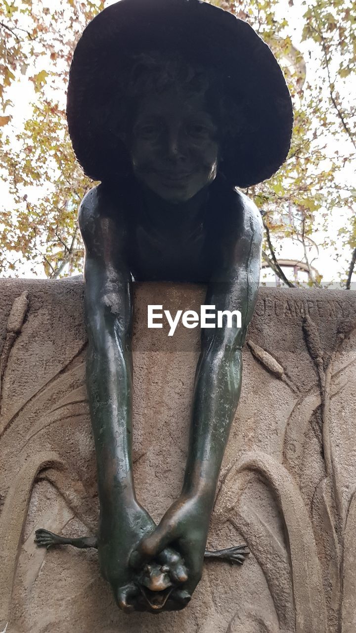 LOW ANGLE VIEW OF FEMALE STATUE AGAINST TREE