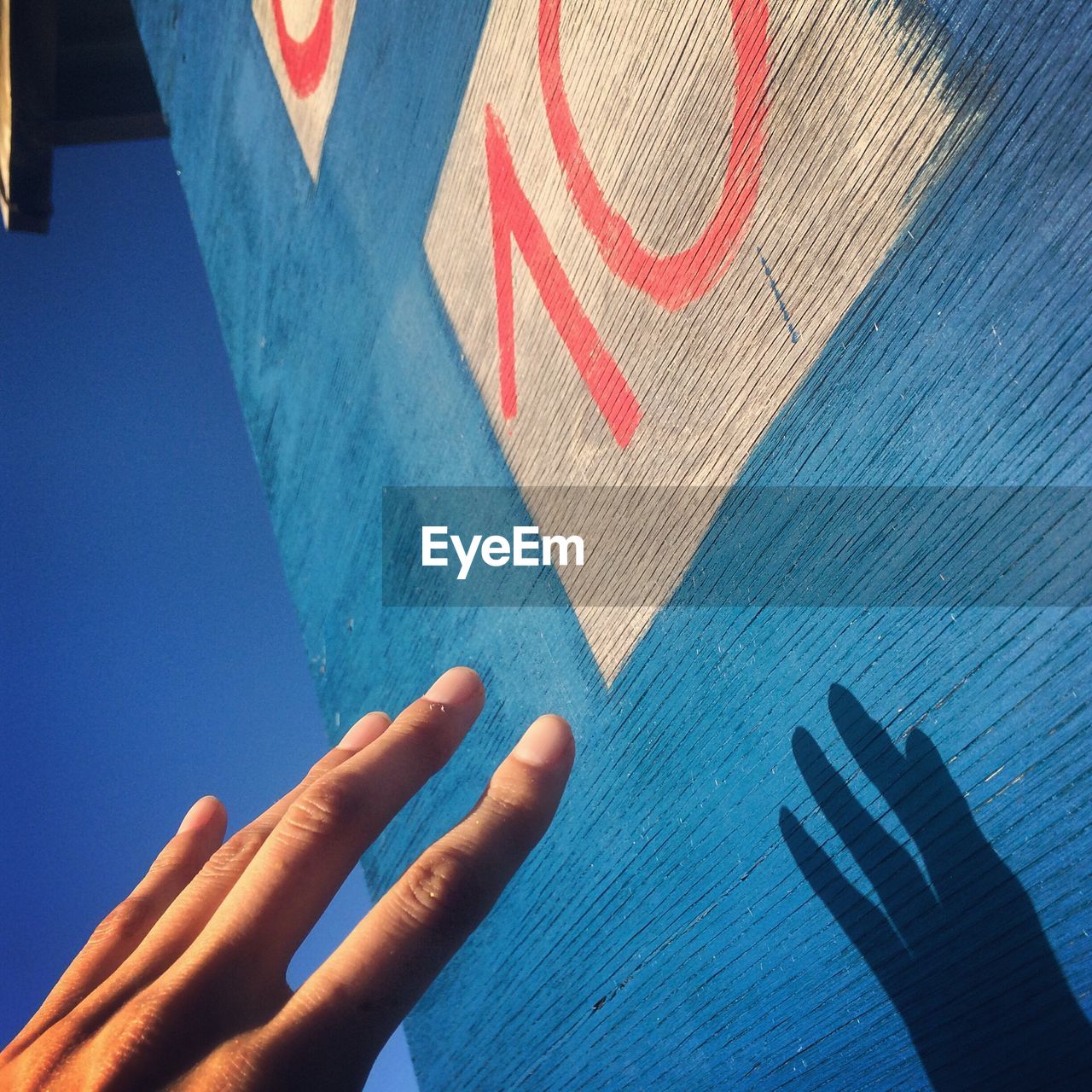 Close-up of human hand against blue wall