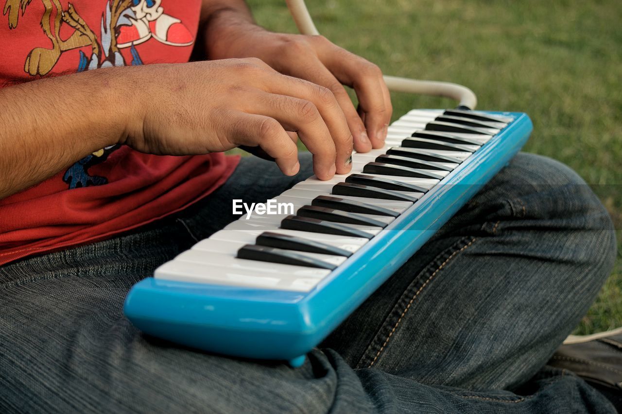 Midsection of man playing synthesizer on field