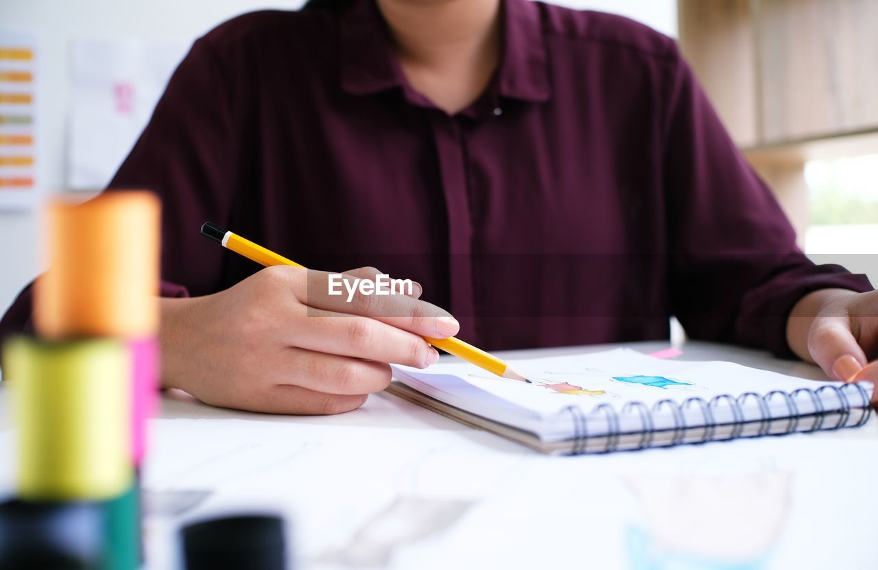 Midsection of fashion designer working at desk