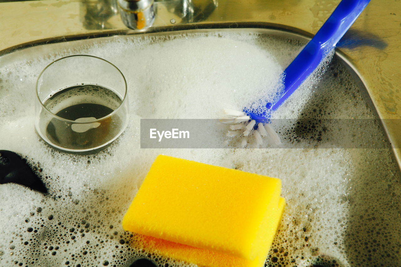 Utensils covered with soap sud in kitchen sink