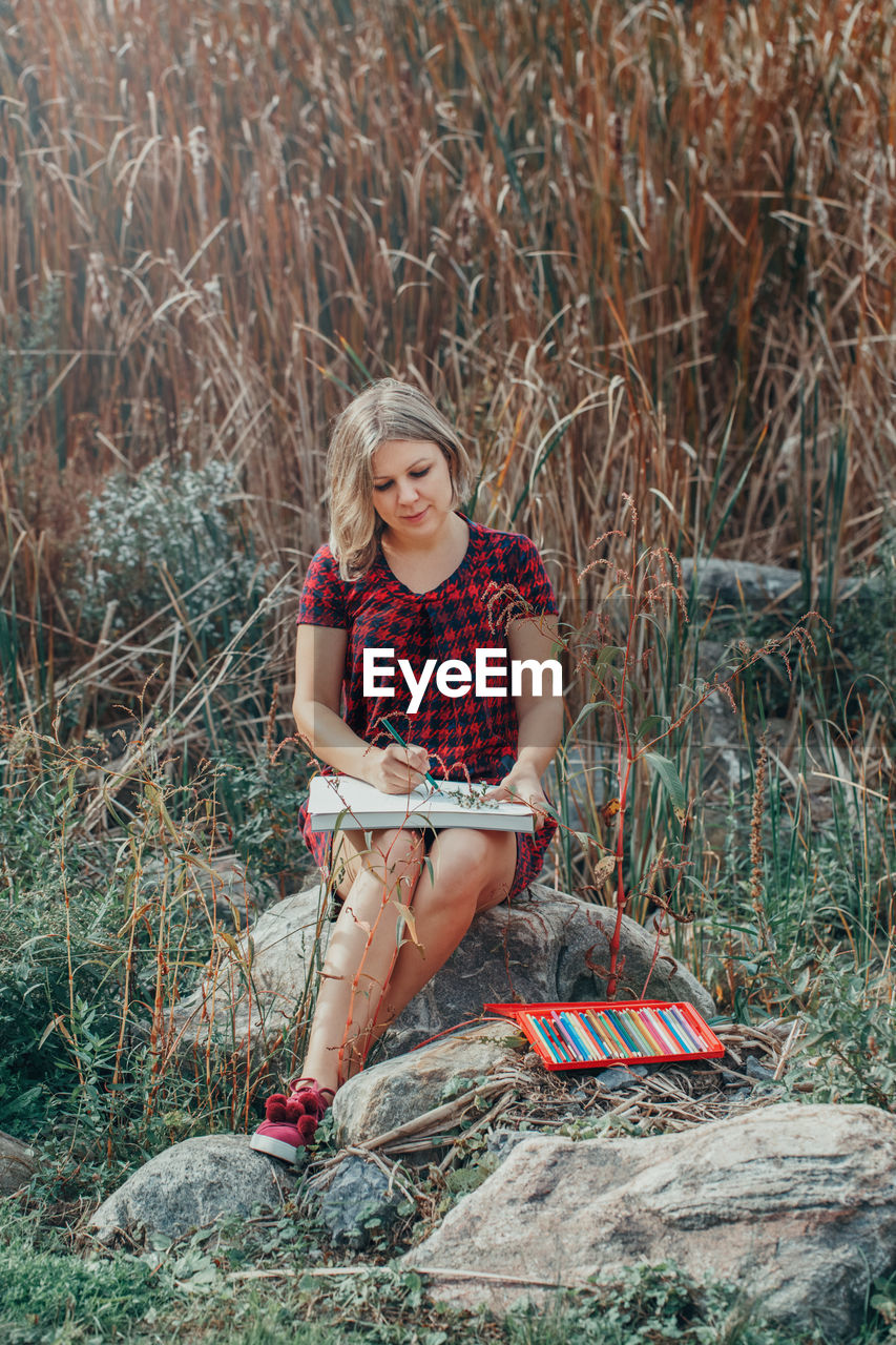 Woman drawing while sitting on grass