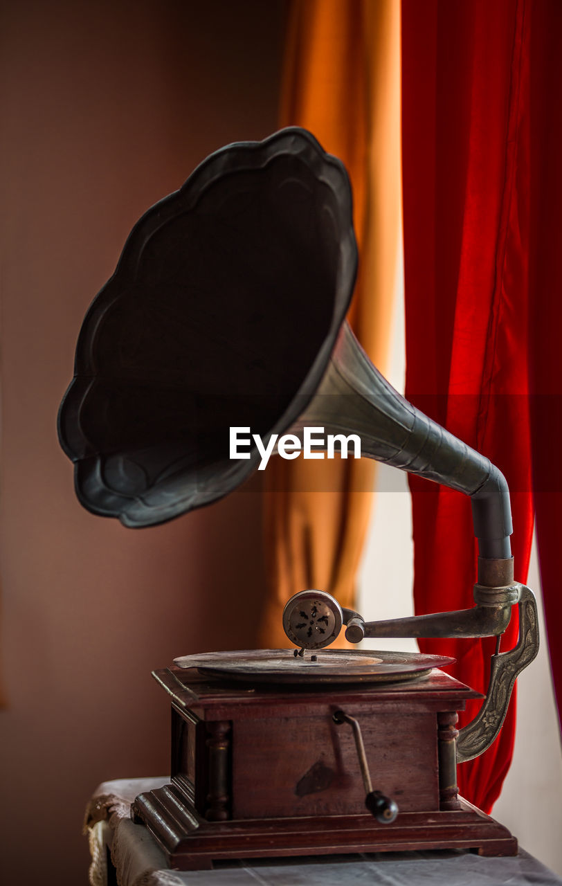 Gramophone on table against curtain at home