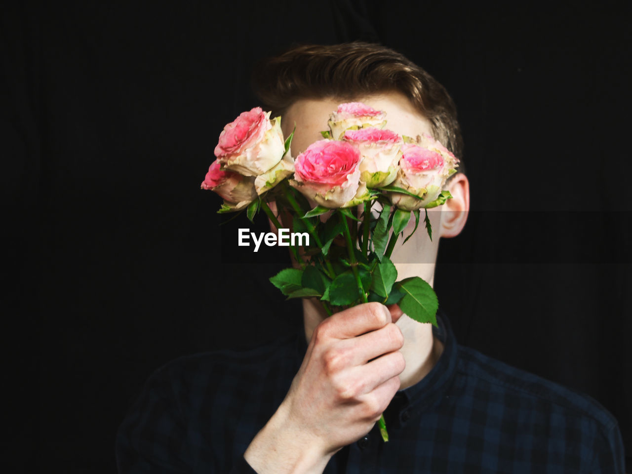 Man holding bouquet against black background