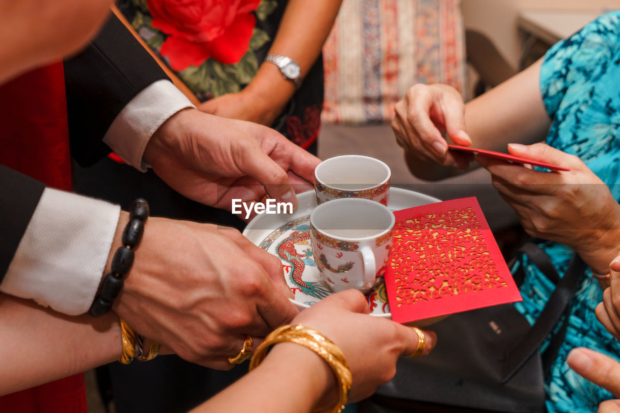 Midsection of man and woman serving coffee to relative at home