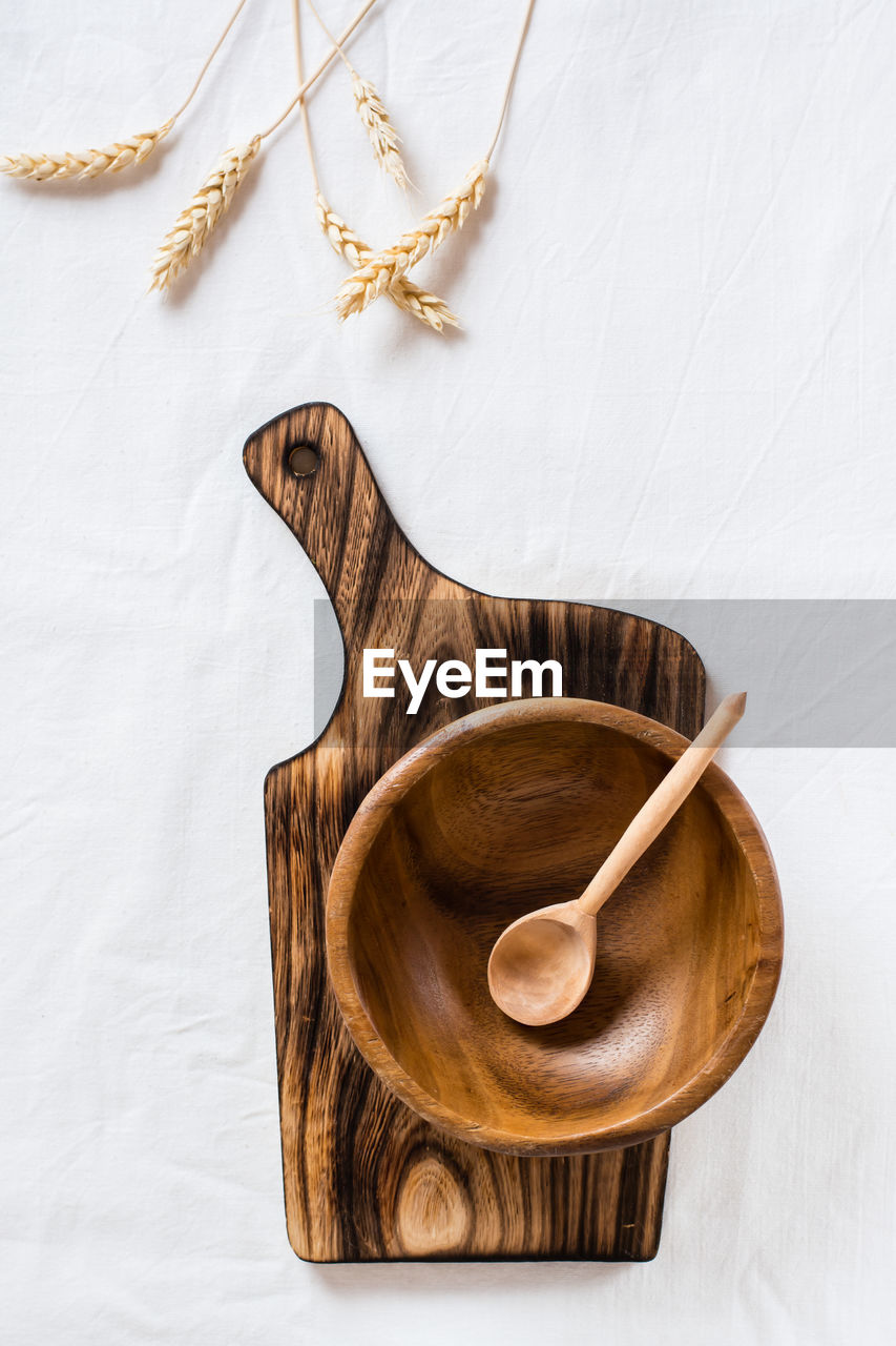 Empty wooden bowl and spoon on cutting board and ears on cloth. top and vertical view. 