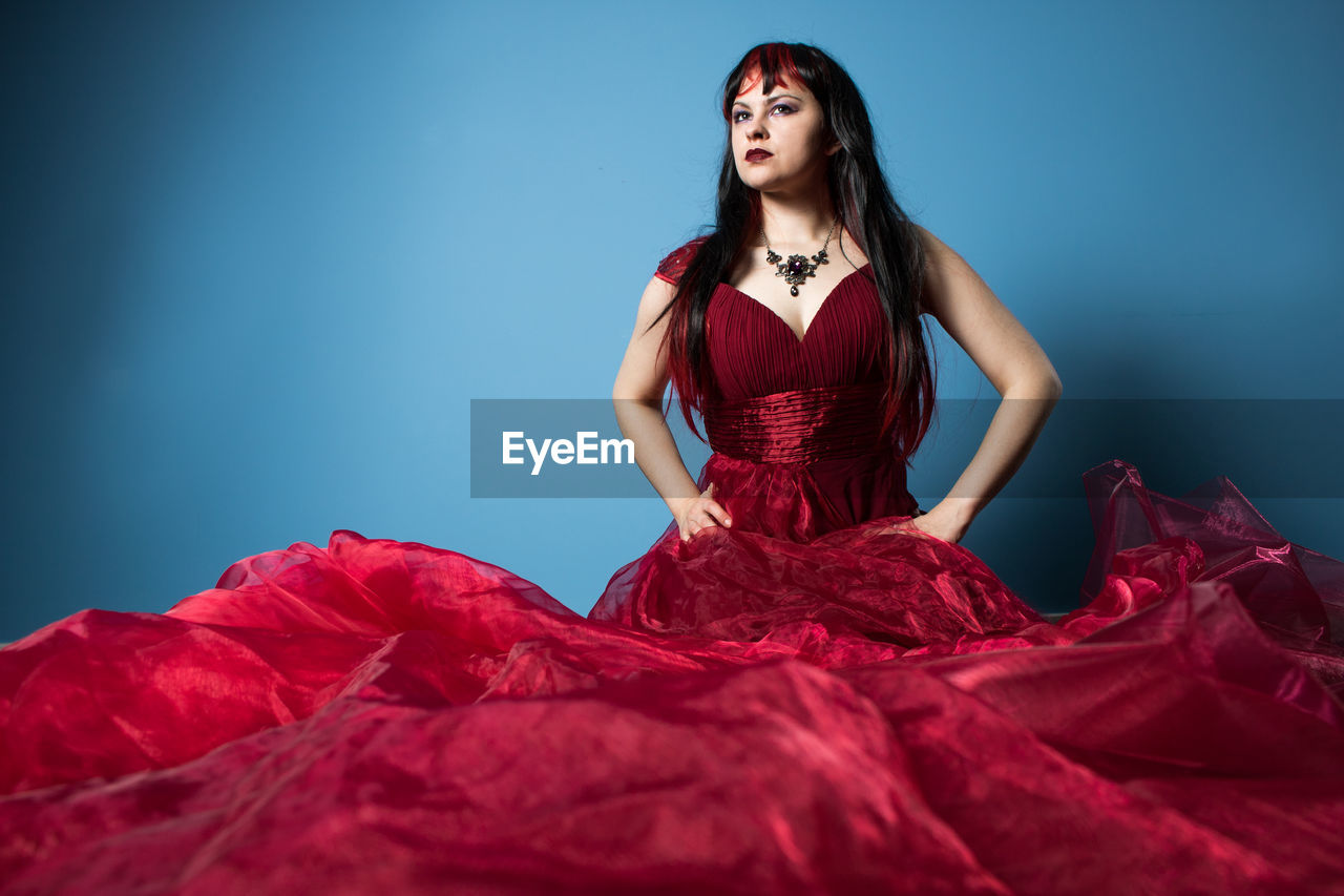 Portrait of beautiful woman standing against blue background