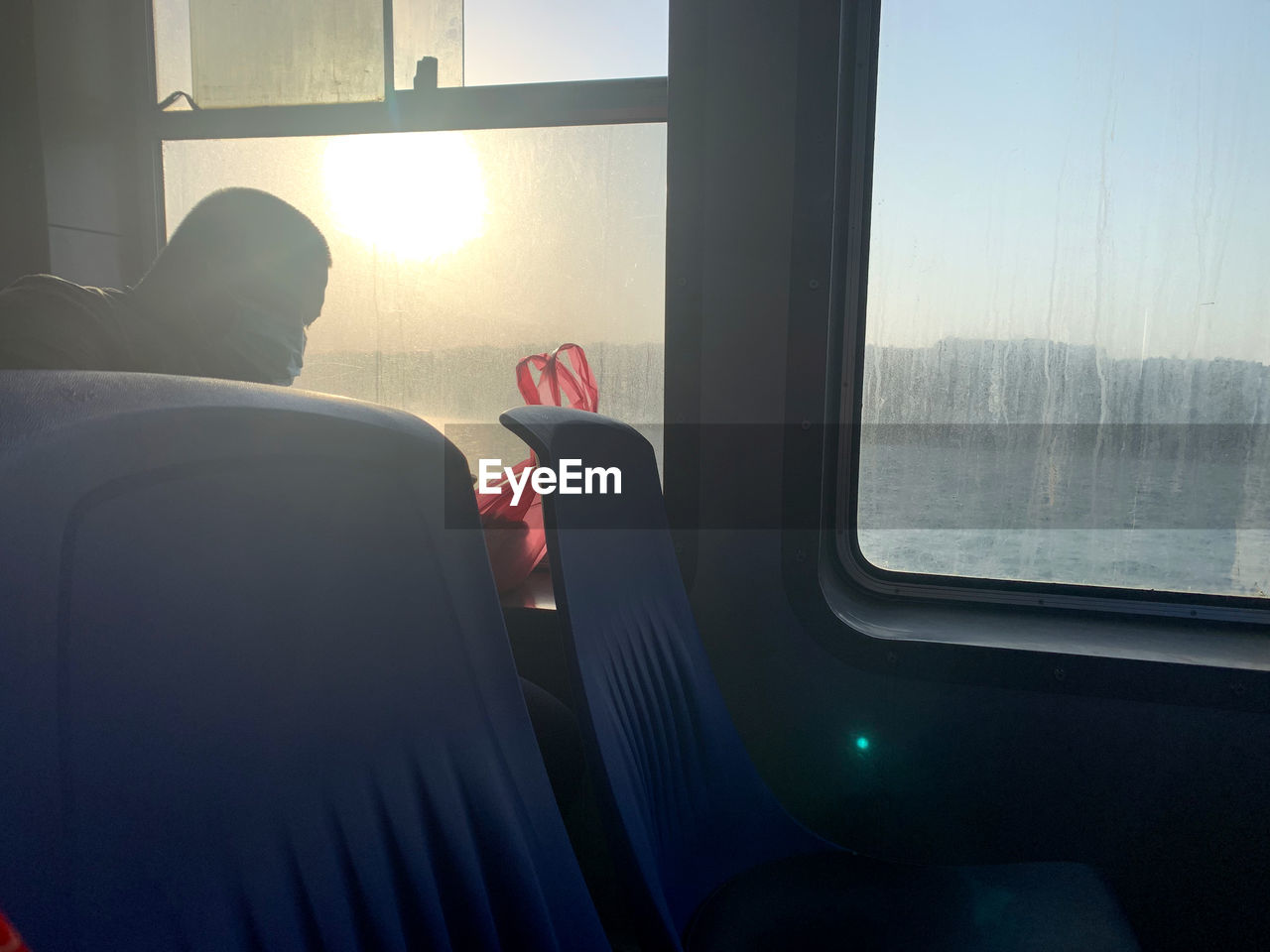 MAN SEEN THROUGH TRAIN WINDOW IN BUS