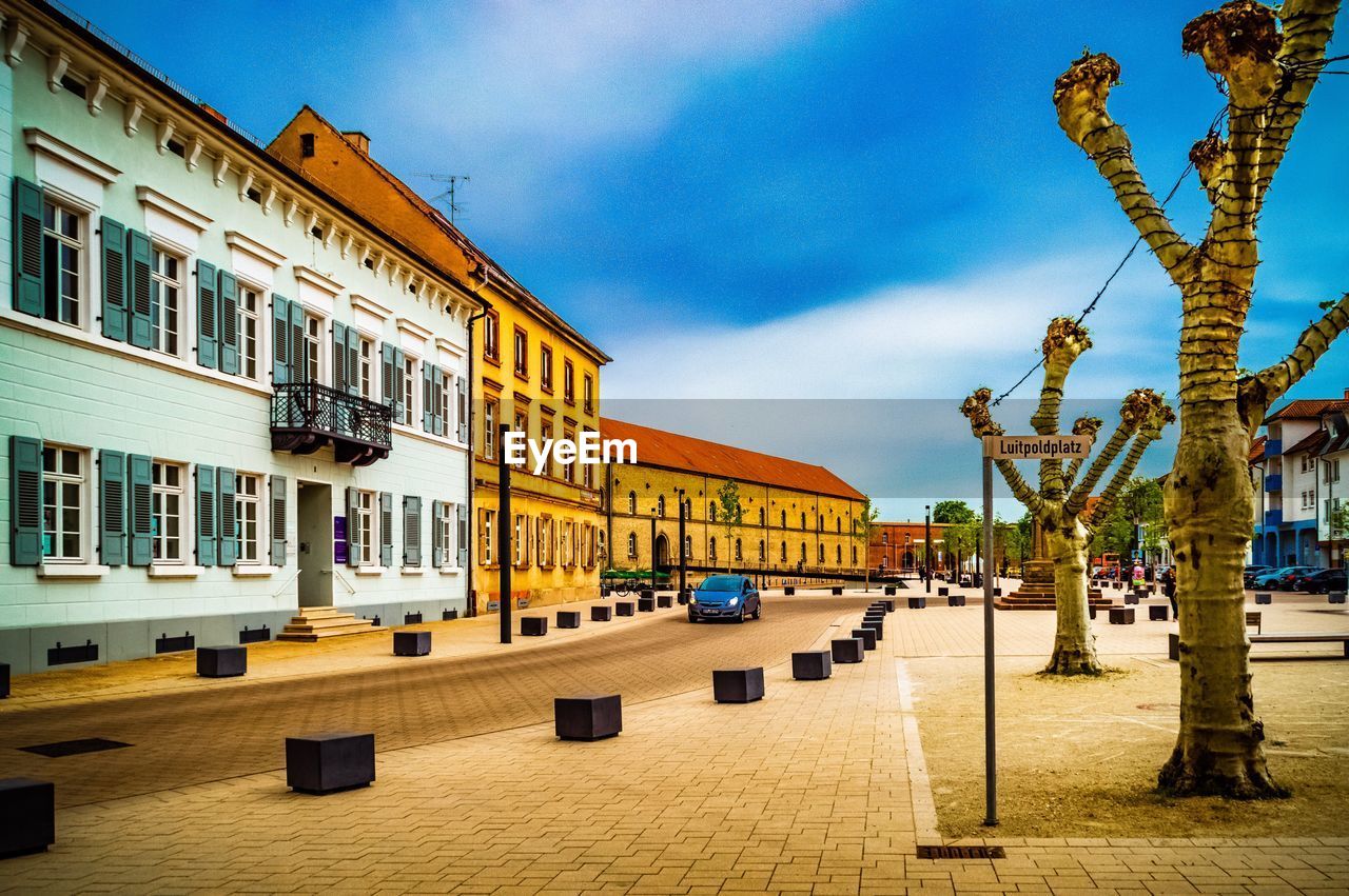 Buildings by street in town against sky