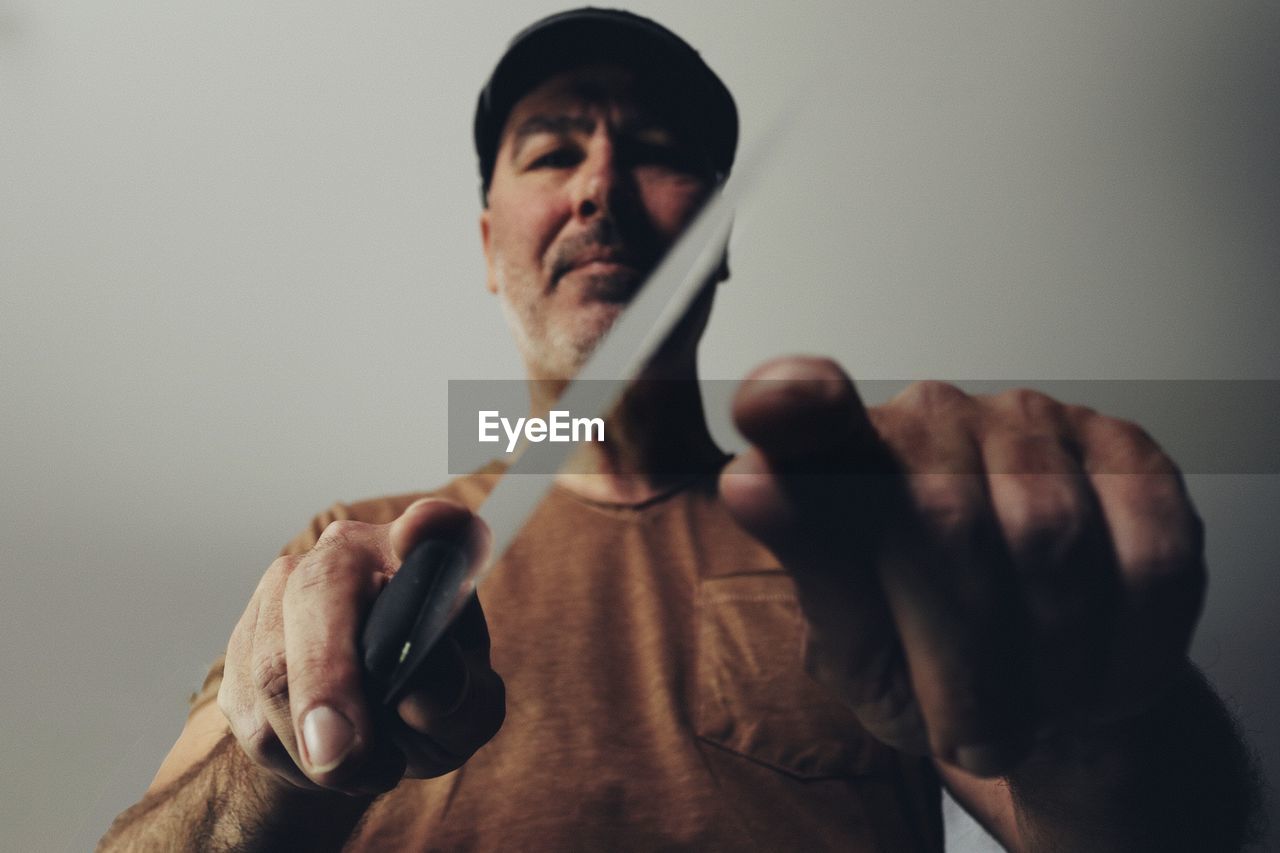 Low angle view of man holding knife against ceiling at home