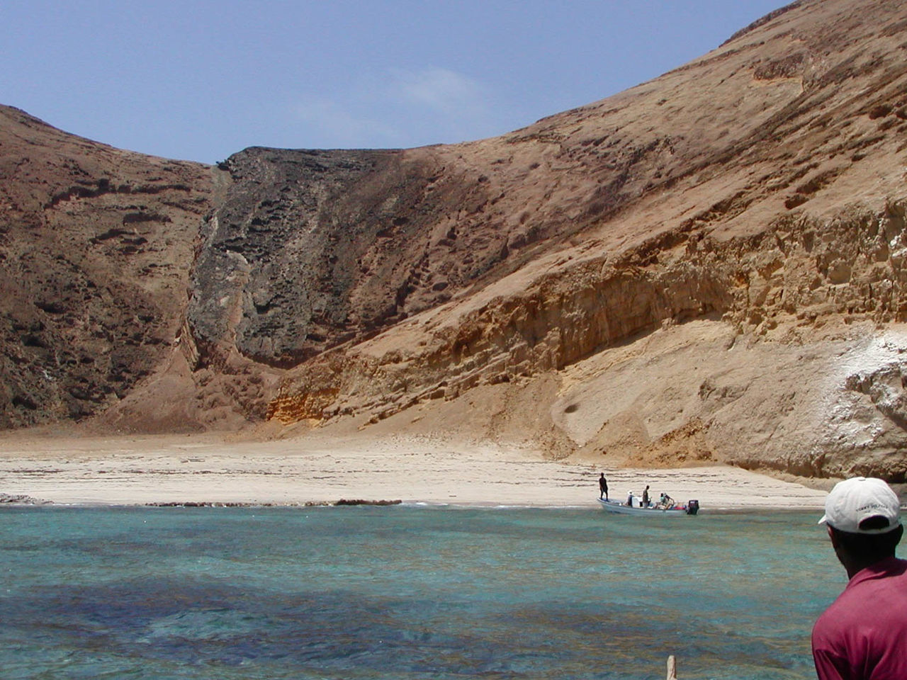 Rear view of man at beach against rocky mountain