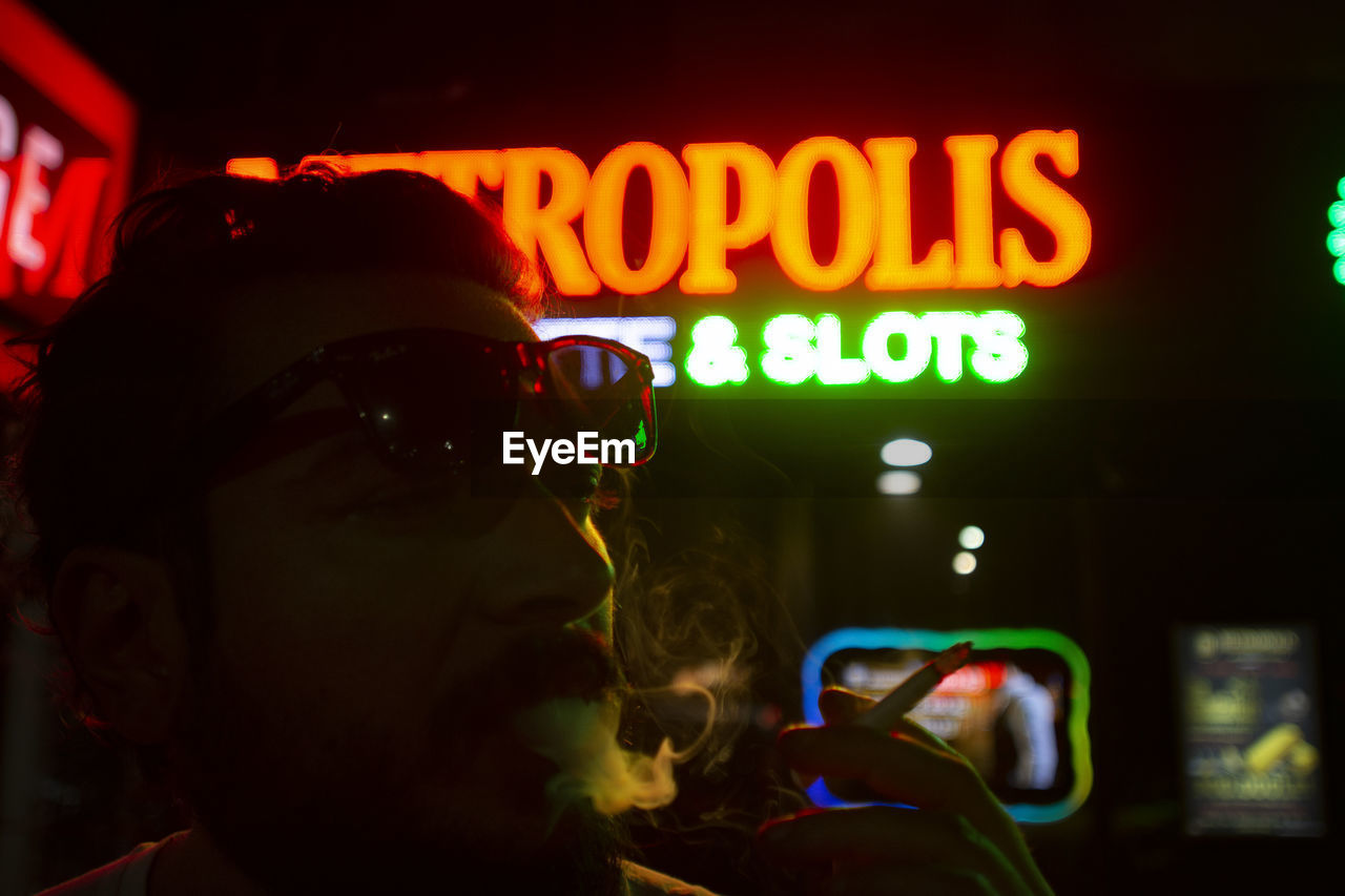 Close-up of man smoking cigarette at nightclub