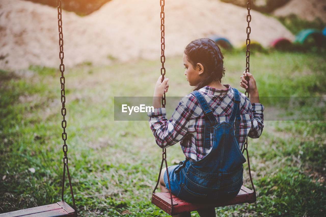 Girl sitting on swing at park