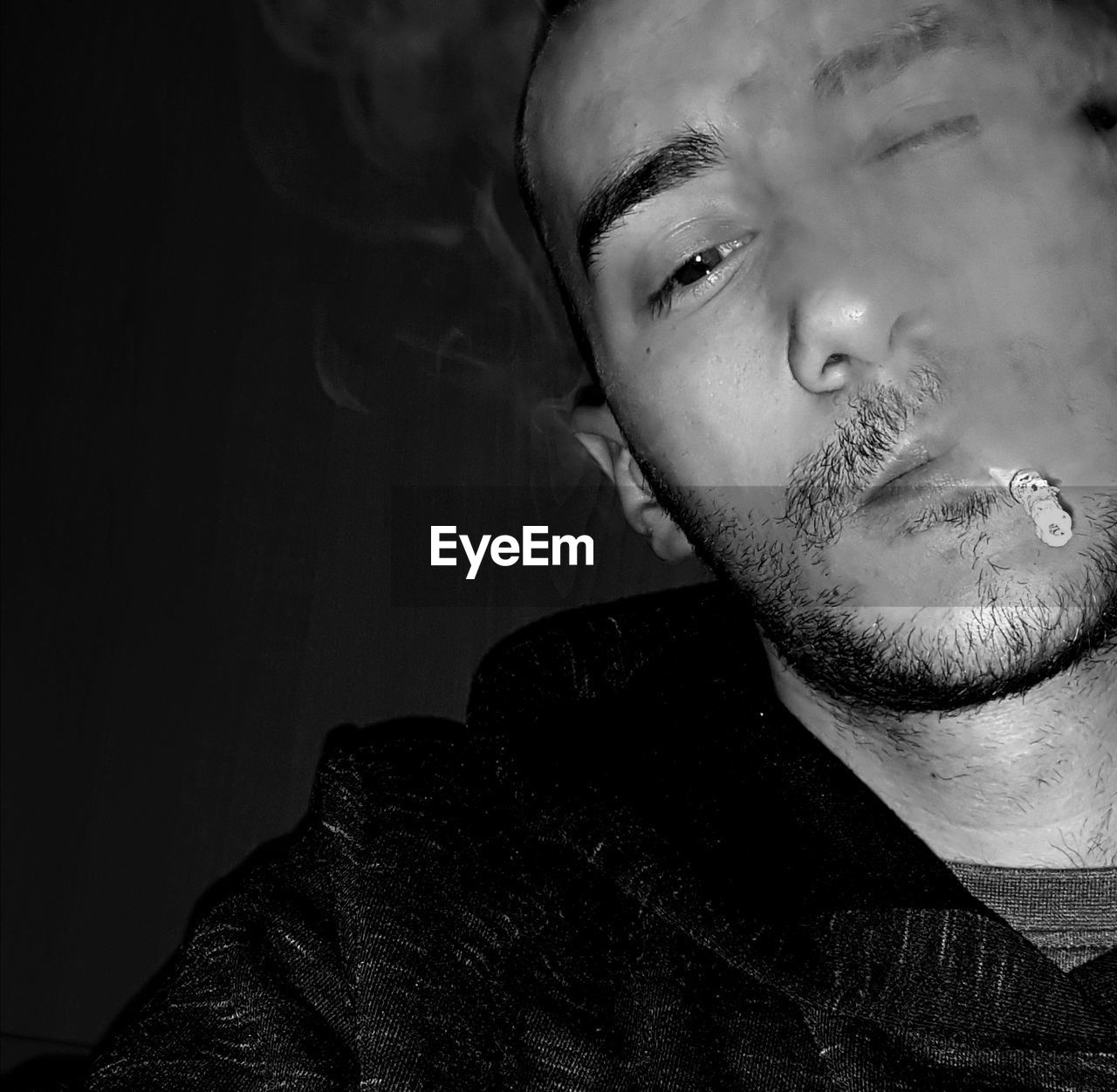 PORTRAIT OF YOUNG MAN SMOKING OUTDOORS