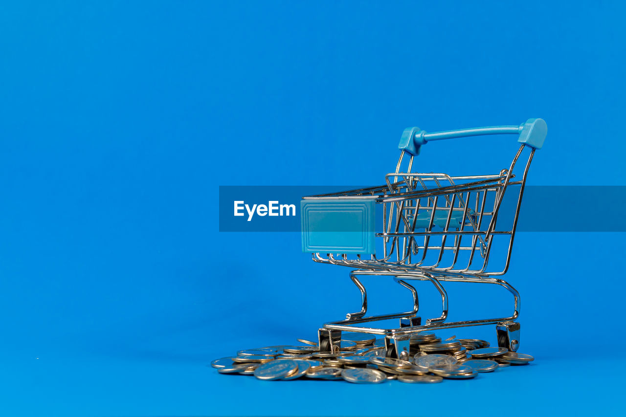 shopping cart, shopping, consumerism, blue, retail, studio shot, supermarket, blue background, store, colored background, copy space, indoors, buying, no people, metal, cut out, finance, cart, business, single object