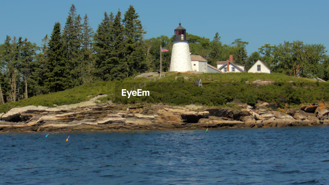 LIGHTHOUSE BY TREES AGAINST SKY