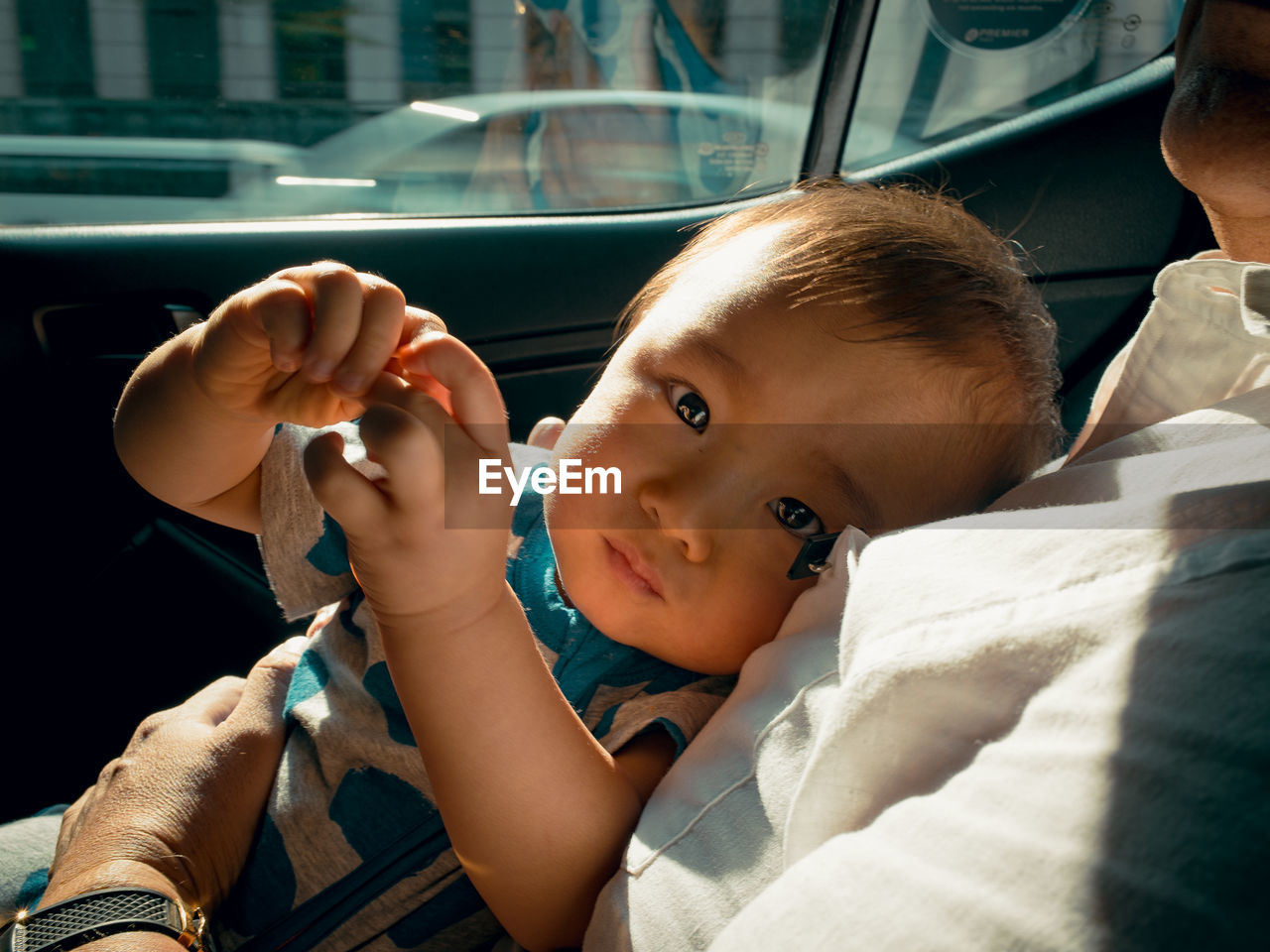 Portrait of cute baby relaxing with father in car