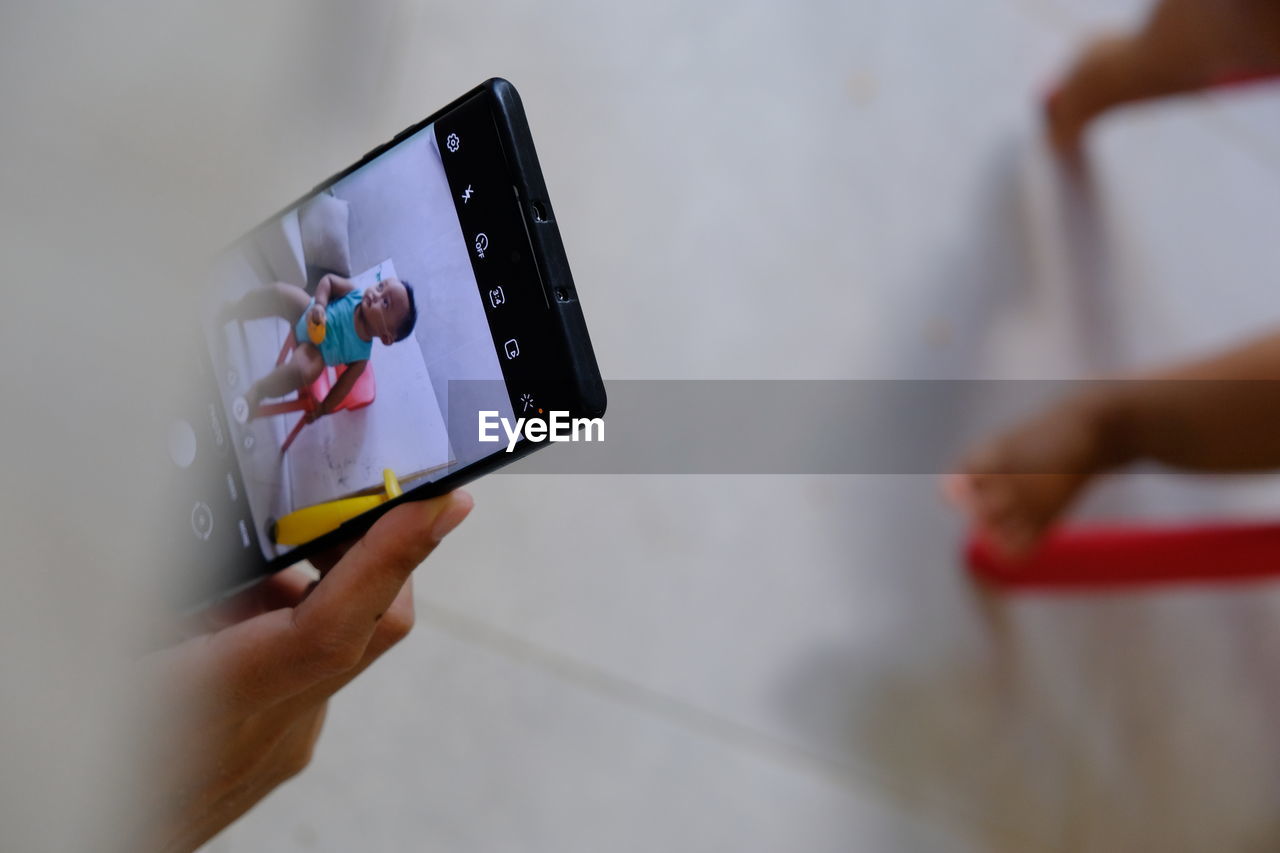 MIDSECTION OF WOMAN HOLDING MOBILE PHONE IN LAPTOP