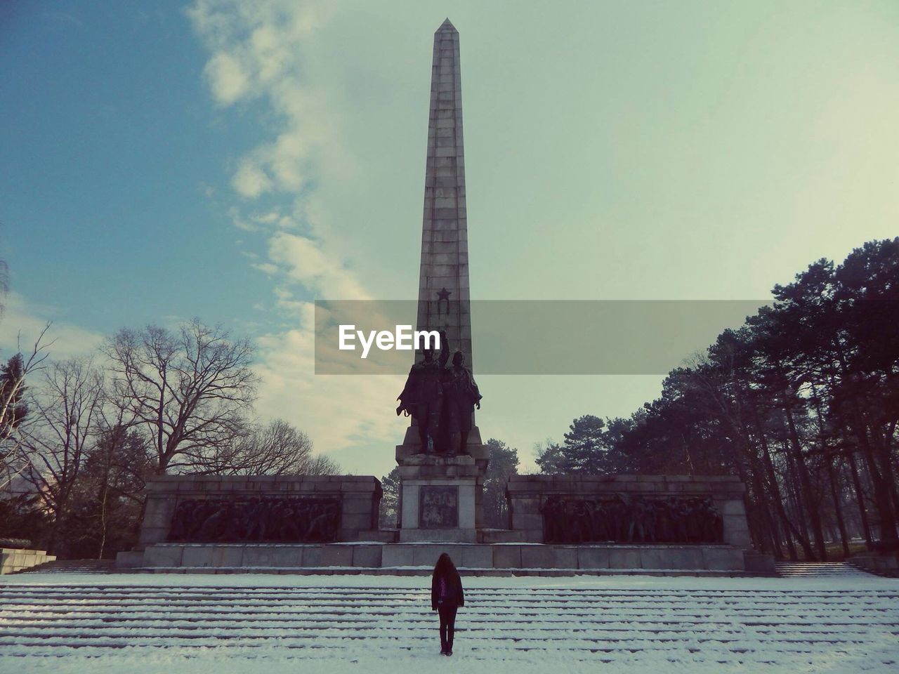 Woman standing against tower in winter