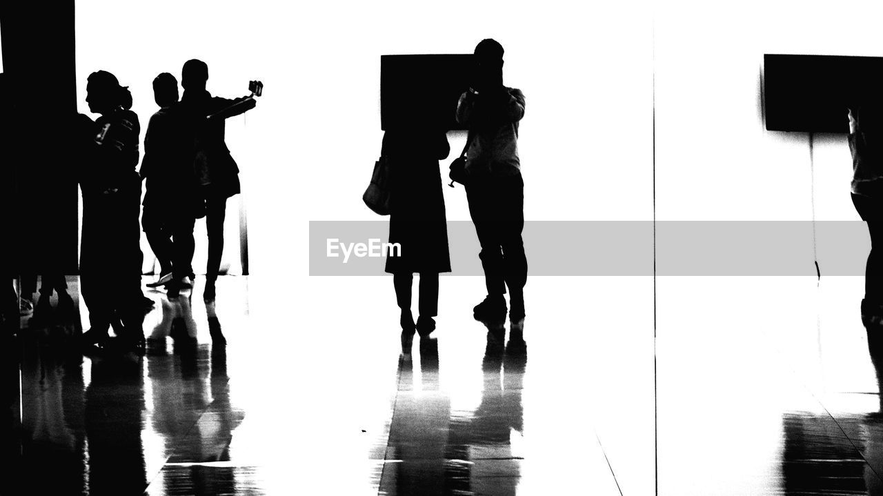 SILHOUETTE PEOPLE STANDING ON REFLECTION OF TWO MEN ON MIRROR