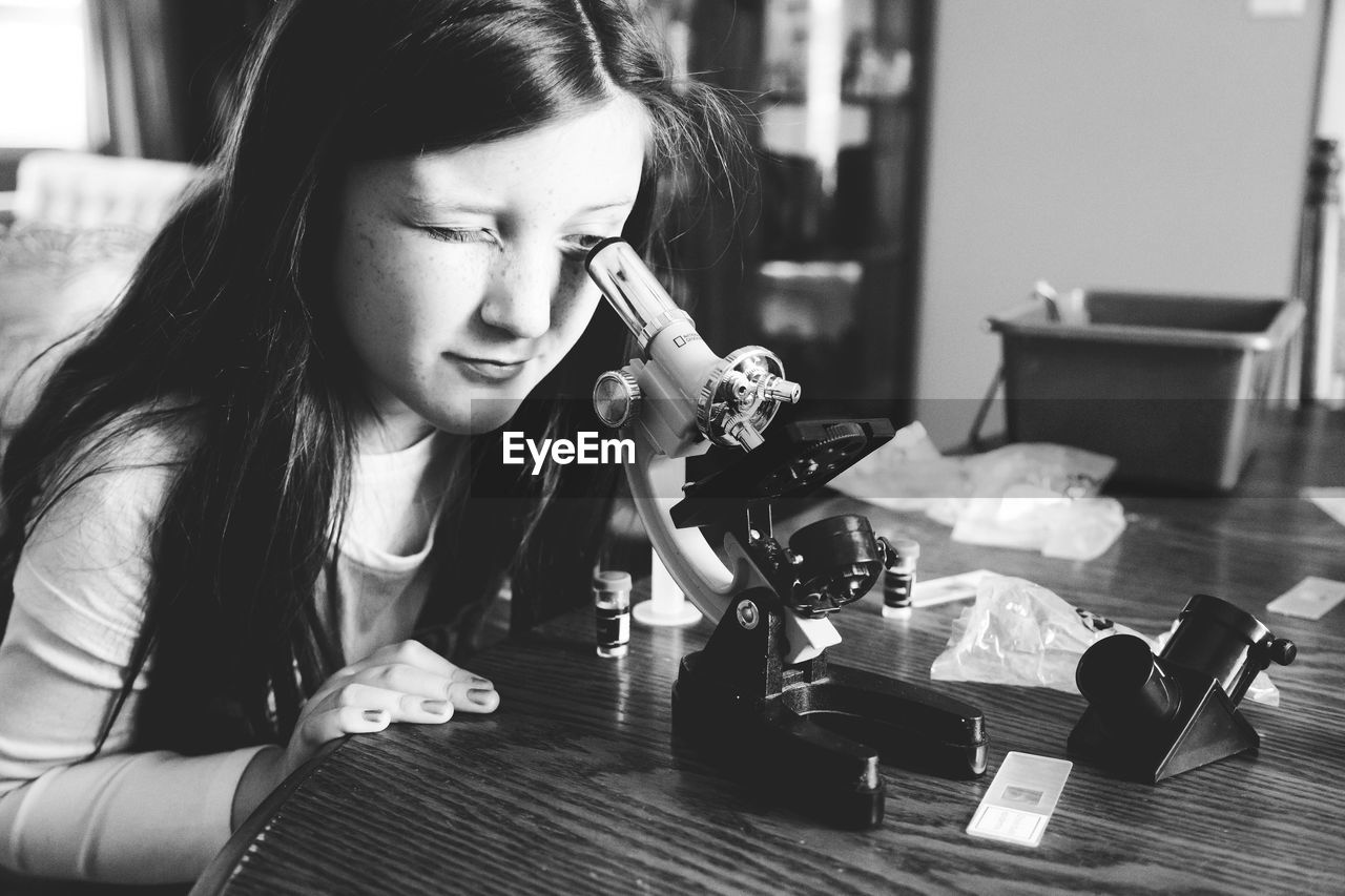 Girl using microscope at table in school