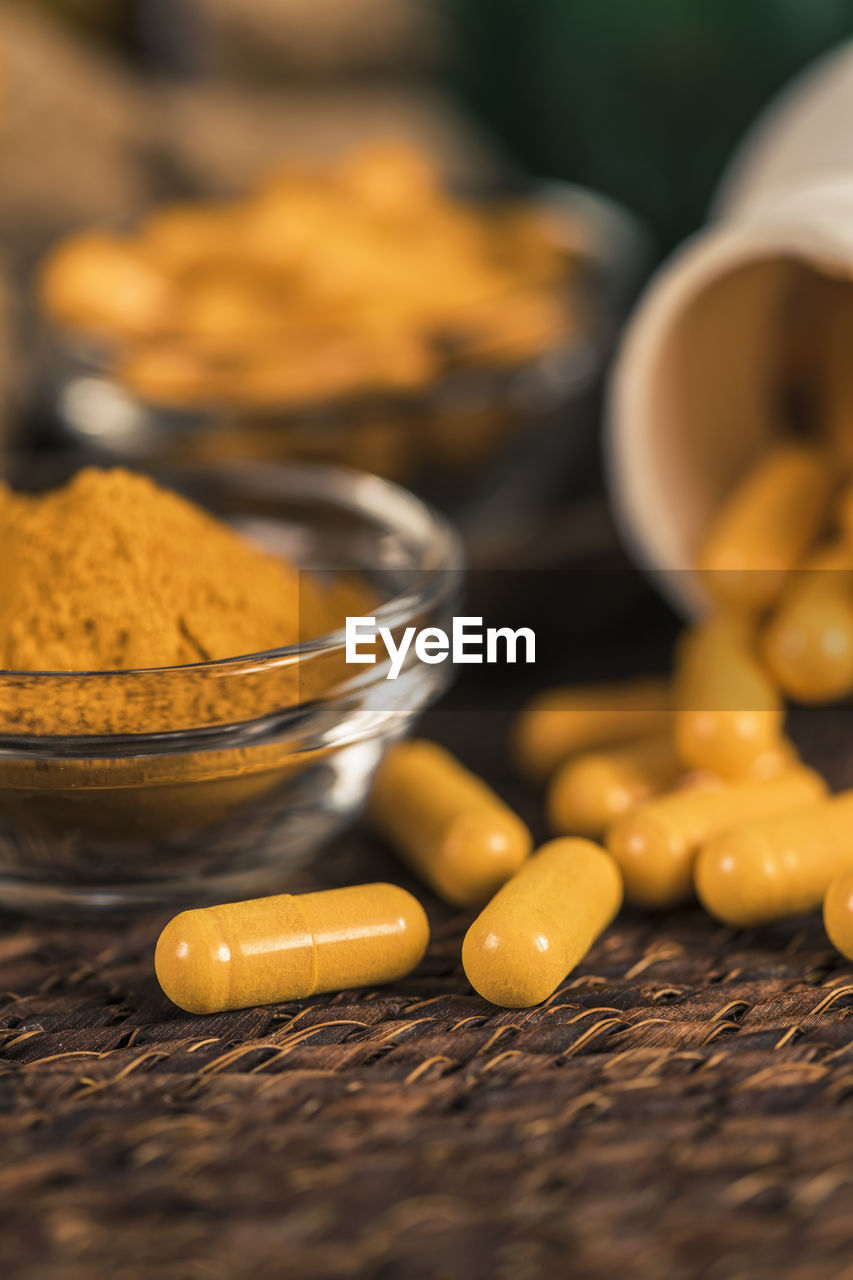 Curcumin herbal supplement capsules and turmeric powder in glass bowl