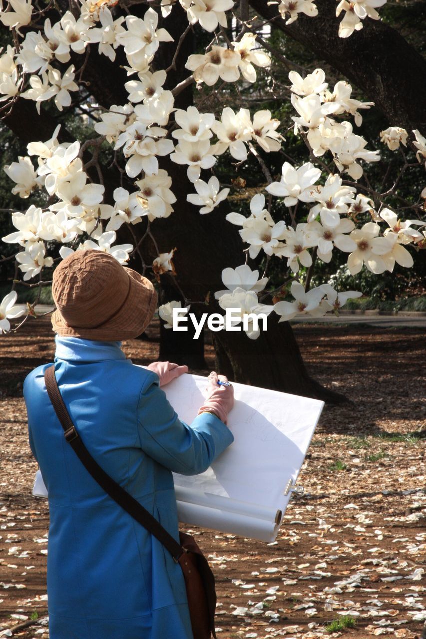 Woman drawing against flowering tree