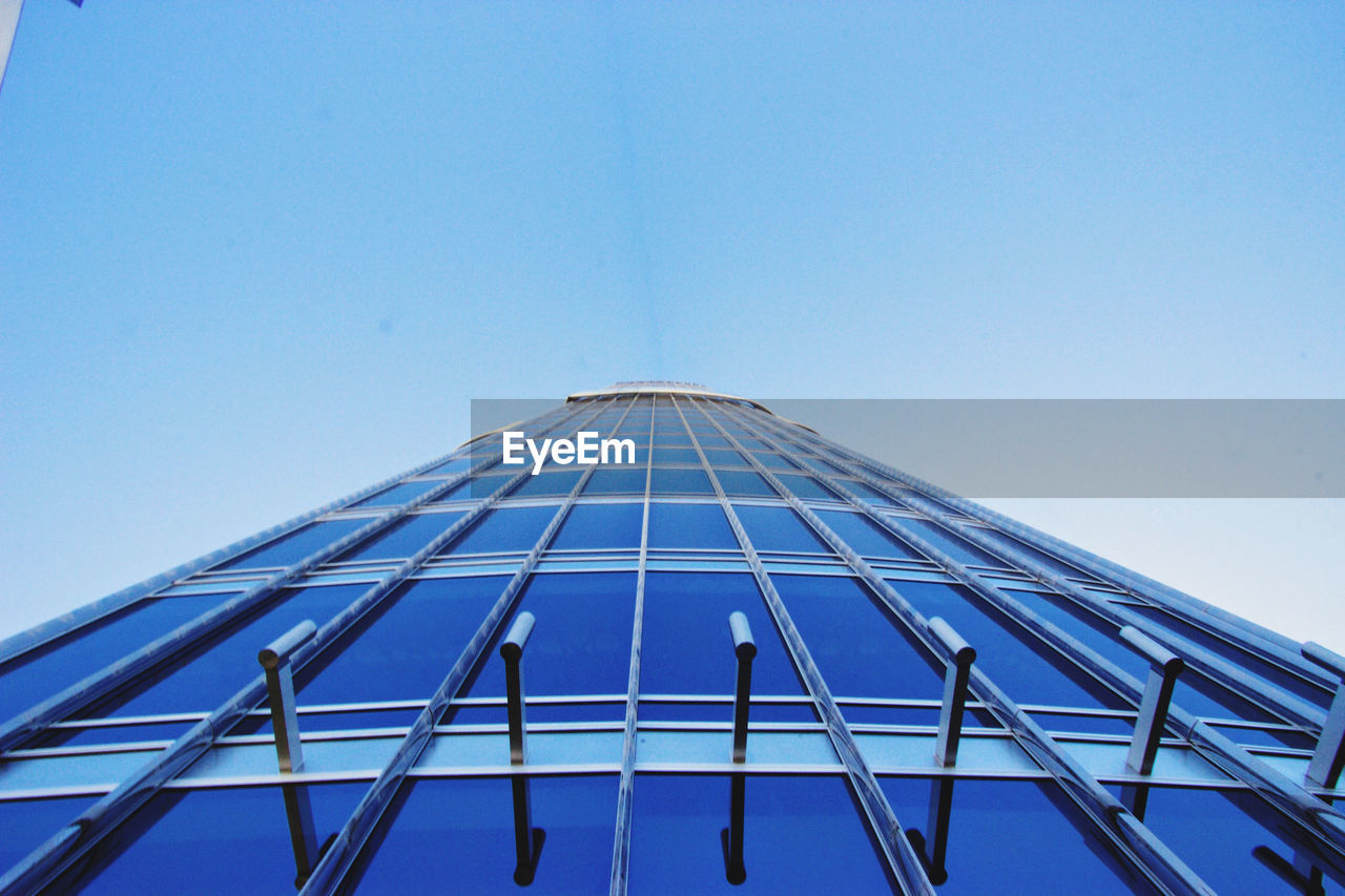 Low angle view of glass building against clear blue sky