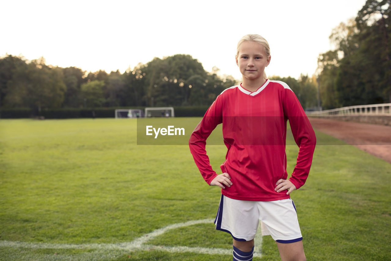 Portrait of confident girl standing on soccer field