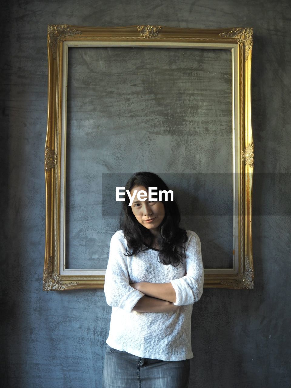 Portrait of woman with arms crossed standing against wall