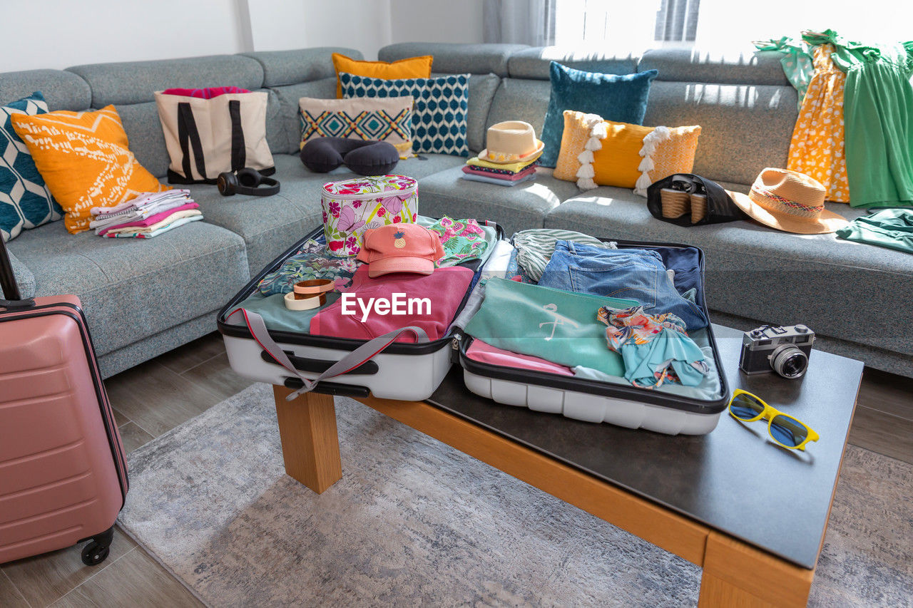 Suitcases and summer clothes waiting to be packed in living room for a travel vacation