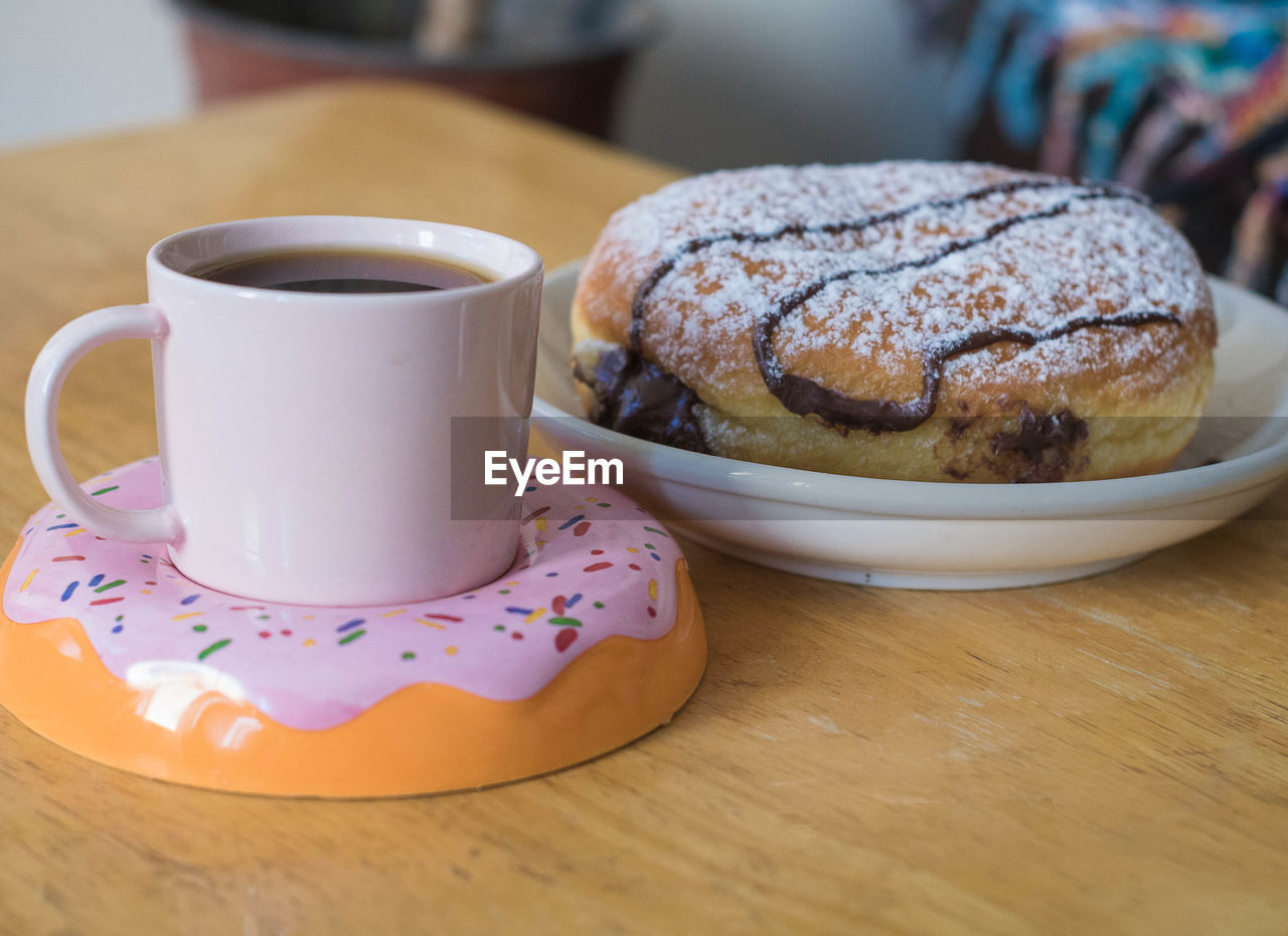 food and drink, food, sweet food, cup, mug, baked, drink, table, sweet, breakfast, dessert, coffee, coffee cup, freshness, hot drink, meal, indoors, plate, cake, sugar, no people, saucer, tea, refreshment, close-up, dish, crockery, focus on foreground, wood, still life, produce, temptation, powdered sugar