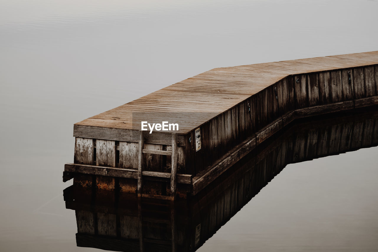 REFLECTION OF BRIDGE IN WATER AGAINST CLEAR SKY