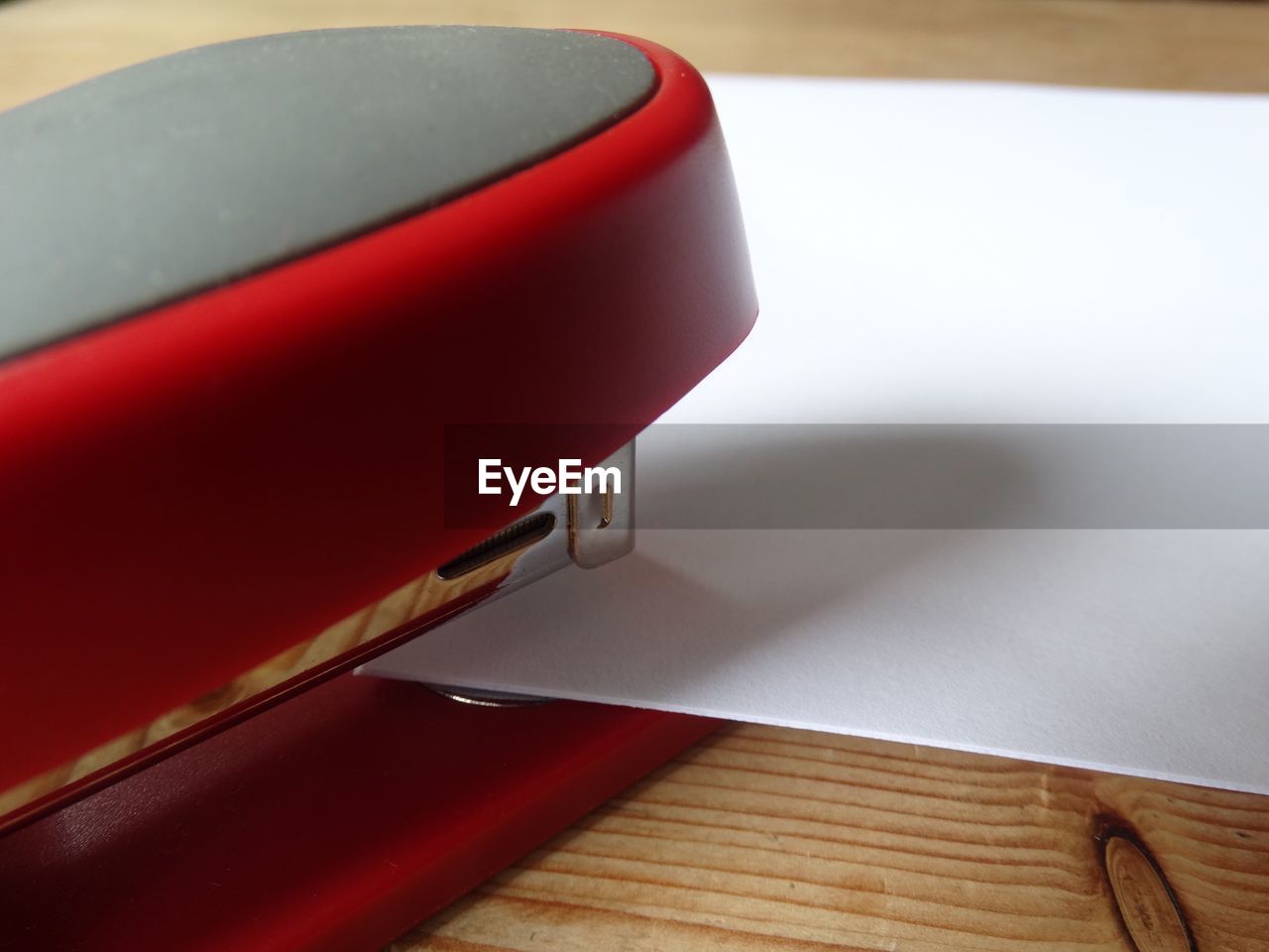 Close-up of paper amidst red stapler on table