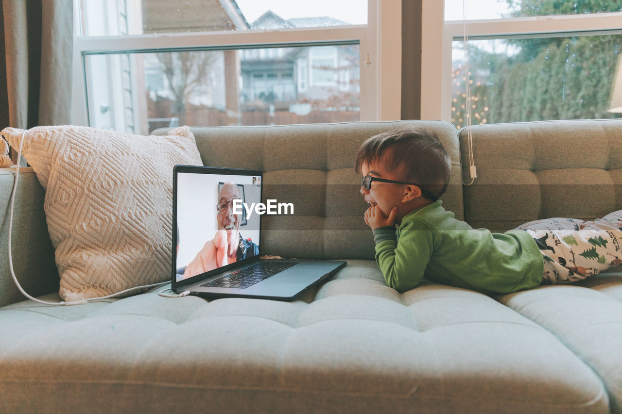 Cute boy sitting on sofa during video call at home